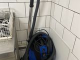 un aspirateur bleu et noir dans un coin de la salle de bains