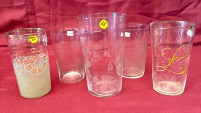 quatre verres ornés d'autocollants jaunes sont alignés sur une nappe rouge