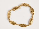an image of a gold bracelet on a white surface