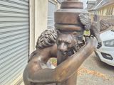 a bronze statue of a man holding a bird on his head