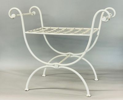 a white iron bench with a basket on it