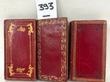 trois livres en cuir rouge avec des bordures dorées et une bordure dorée