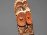a close up of a wooden mask on a stand