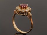 a close up of a gold ring with a ruby stone and diamonds