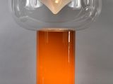 an orange glass table lamp with a white base and a clear glass shade