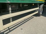 a green semi truck with a flat bed parked in a parking lot