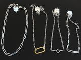 a group of four silver and gold necklaces on a black surface