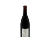 the bottle of wine is sitting on a white surface