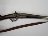 a silver plated rifle with a wooden handle and a leather strap