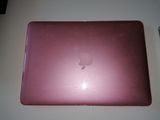 un ordinateur portable Apple rose posé sur une table blanche