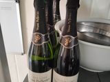 three bottles of wine sitting on a shelf next to a bowl