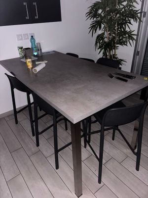 une table avec quatre chaises et une plante dans un coin