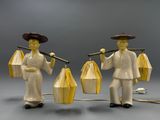 two figurines of a man and a woman holding umbrellas