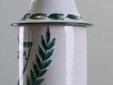 a white jar with a green leaf design on it