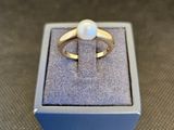 un gros plan d'une bague en or sertie d'une perle blanche