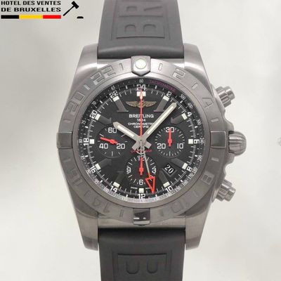une montre noire avec une trotteuse rouge, montée sur un bracelet en caoutchouc noir