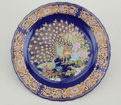 a blue plate with a peacock and flowers on it