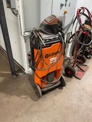 an orange and black machine sitting in a garage next to other equipment