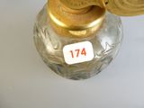 un vase en verre avec un couvercle doré posé sur une table blanche