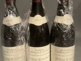 three bottles of wine wrapped in plastic sitting on a table
