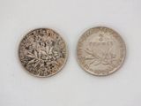 two coins that are sitting side by side on a white surface