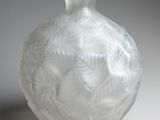 a white vase with a leaf design on it