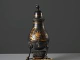 un vase noir et doré posé sur un socle en métal