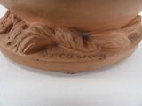 a brown vase with a bird on it on a table