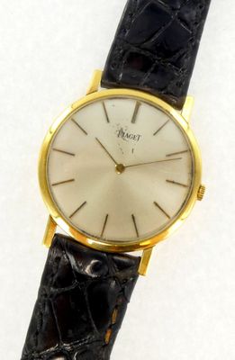 une image représentant une montre en or avec un cadran blanc et un bracelet en cuir noir