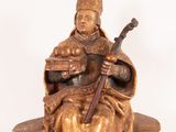 statue of a man sitting on a pile of books with a book in his lap
