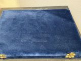 a blue velvet covered box with gold handles on a table