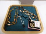 a wooden tray with a necklace and a box of jewelry on it