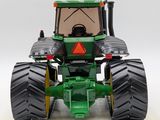 a green toy tractor with large tires on a white surface