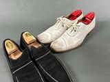 two pairs of men ' s shoes are lined up on a gray surface