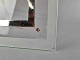 a glass frame with a metal handle on a table