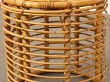 a wicker stool with a wooden seat on a cement floor