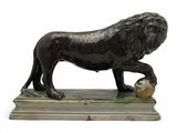 statue of a lion with a ball in its paws