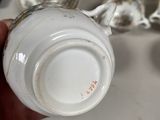 a person holding a cup in front of a bunch of silver spoons