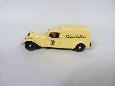 un petit camion jouet jaune posé sur une surface blanche, avec un fond blanc