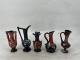 several different colored glass vases are lined up on a white surface