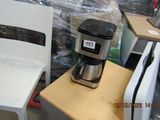 a coffee maker sitting on top of a table next to a chair