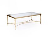 une table basse dorée avec un plateau en verre et des pieds en métal