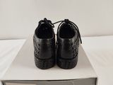black leather shoes with laces on top of a box on a white surface