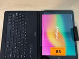 une tablette avec un clavier posée sur un bureau, à côté d'une tasse de café