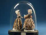 two figurines of two women in dresses under a glass dome