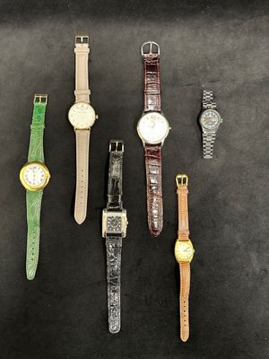 four different watches are lined up on a black surface