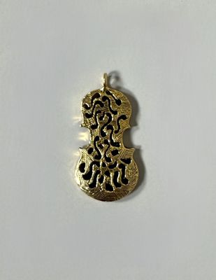 a close up of a gold pendant on a white surface