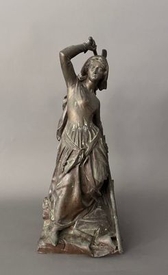 une statue antique en bronze représentant une femme tenant un oiseau dans la main