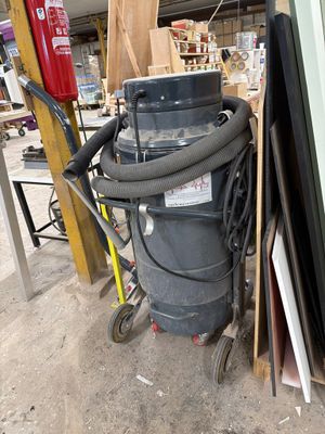 un dépoussiéreur posé à côté d'un tas de vieilleries dans un garage