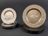 three silver plates with designs on them on a black surface